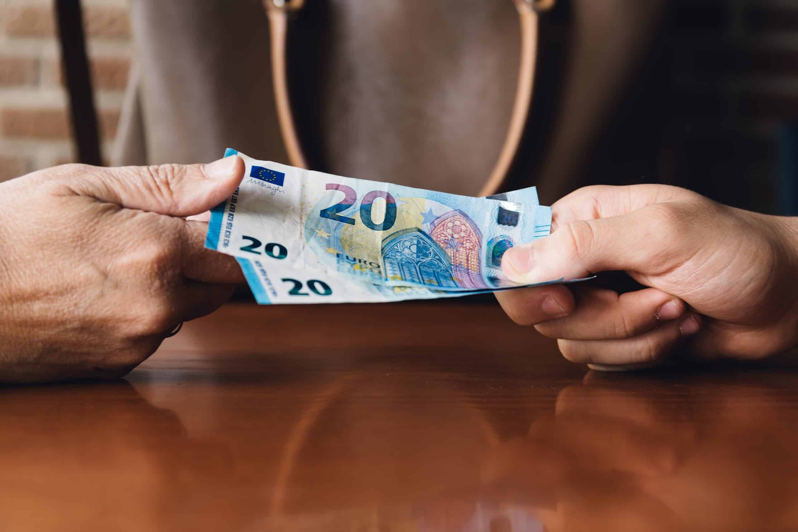 hand of woman is giving euro money to a young man